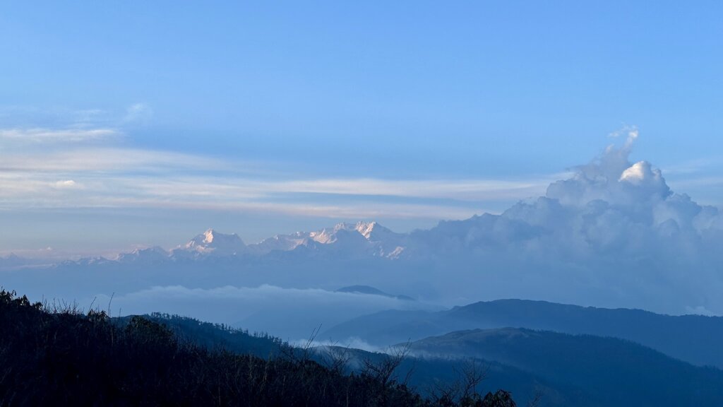 Majestätische, schneebedeckte Gipfel über einer Wolkendecke im Sonnenlicht.