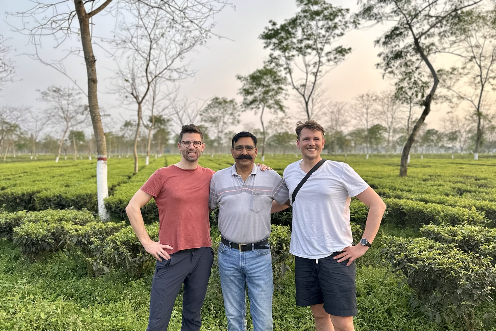 Die Gründer des Assam-Projekts posieren mit einem lokalen Partner in einer Teepflanzung.